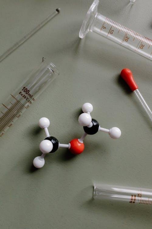 Close-up of a molecular model surrounded by laboratory equipment like pipettes and test tubes